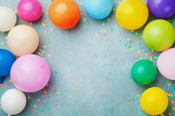 Colorful balloons and confetti on blue table top view. Festive or party background. Flat lay style....