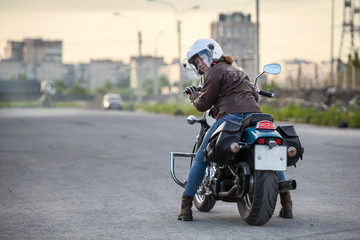 Woman a motorcyclist ready to stard riding on motorbike on asphalt road, copy space