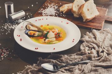 Fototapeta na wymiar French seafood soup with white fish, shrimps and mussels in plat
