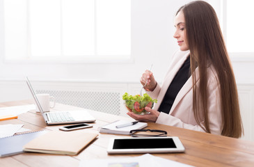 Young business woman eating salad at office