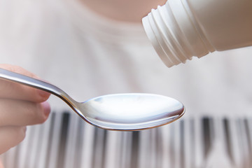 Woman's hand pouring medicine syrup in spoon