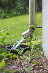 Heavy rain outdoors. Drains are filled with water. Gutter pipe flooding with water.