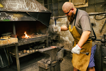 Blacksmith with beard working in his workshop