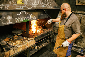 Blacksmith with beard working in his workshop