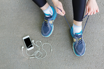 Woman tying shoes laces before running top view