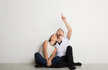 Obraz premium Couple looking up, sitting on floor