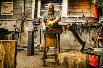 Blacksmith with beard working in his workshop