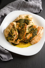 Tasty roasted chicken breast with pesto sauce. Dark still life