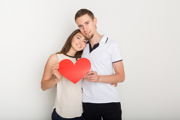 Young happy couple in love holding red paper heart