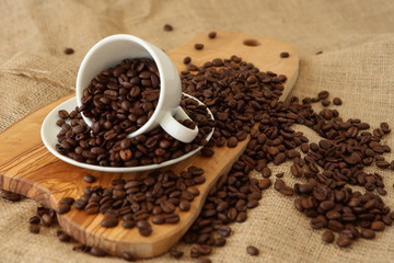 A porcelain cup and coffee beans on the wooden board