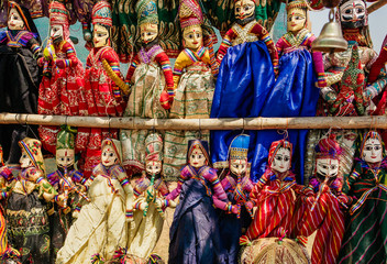 Obraz premium Souvenir toys of traditional Indian market. Faces of funny handmade dolls in old costumes for children in Asia