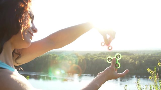 Beautiful woman balancing two fidget spinners on thumbs, slow motion.