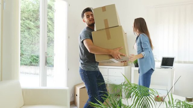 happy young couple student roommate packing boxes and moving furnitures during their move into new home flat apartment