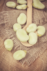 Green fresh broad beans on old wooden table.