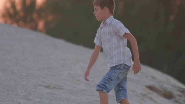 The boy is walking along the beach at sunset. Active rest of the child.