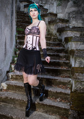 Young beautiful pin up glamour girl with green color hair, high boots on old stone vintage stairs