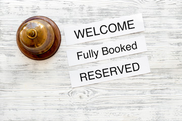 At the hotel. Words welcome, fully booked, reserved on light wooden table top view copyspace