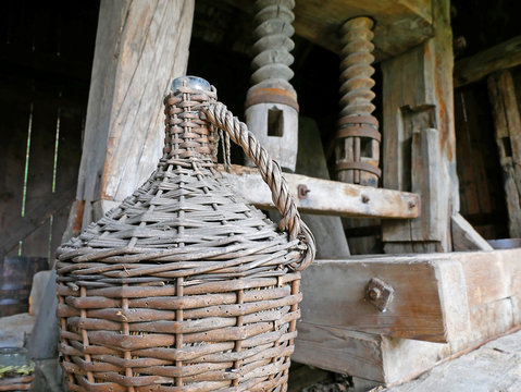An ancient wooden Wine press. Wine demijohn in the foreground.