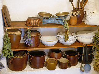 Fototapeta na wymiar Old kitchen utensils, mugs, bowls, kitchen scales, wooden spoons on the shelf.