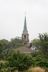 Fototapeta na wymiar Church steeple overlooking sleepy town on a grey summer day