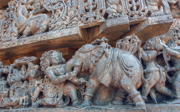 Elephant and ancient people on stone wall background on the Hindu temple. Mythical scenes and designed patterns of 12th century Hoysaleshwara temple in Halebidu, India