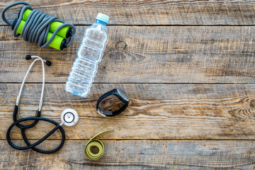 Fototapeta premium Fitness for loosing weight. Jump rope, measure tape and water on wooden background top view copyspace