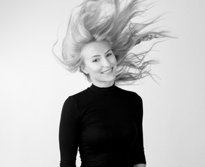 Jugendliche Frau vor weißer Wand mit fliegenden nach oben stehenden Haaren