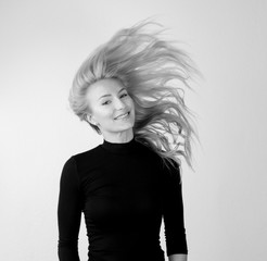 Jugendliche Frau vor weißer Wand mit fliegenden nach oben stehenden Haaren