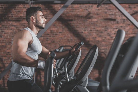 Serene unshaven athlete making exercise in gym