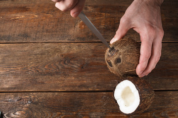 Coconuts in process of opening by knife. Tropical fruit on brown wooden background and free space © golubovy