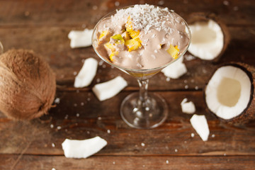 Demonstration of culinary art of fresh fruit salad with coconut flakes in restaurant. Sweet dessert with topping on wooden background
