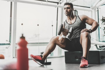 Serious man taking exercise with equipment