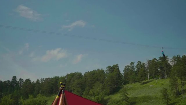 View of girl riding zip line on sunny summer afternoon with blue sky behind