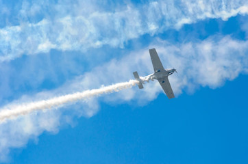 White turboprop airplane with a trace of white smoke against a blue sky
