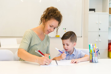 teacher woman drawing with child boy in a classroom