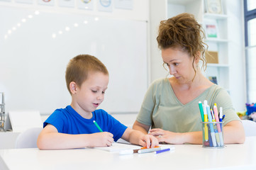 teacher woman drawing with child boy in a classroom