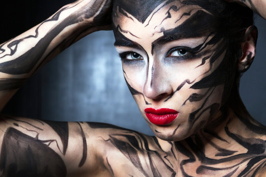 A painted woman with black paint with red lips.