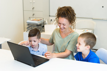 teacher woman learn to use laptop two preschooler boy in the classroom