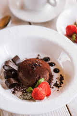 Chocolate fondant on white plate with decoration from strawberry and mint. Delicious dessert serving in restaurant, close up picture