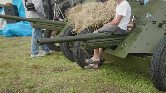 Guy sitting on cannon with hay on it during outdoor exposure