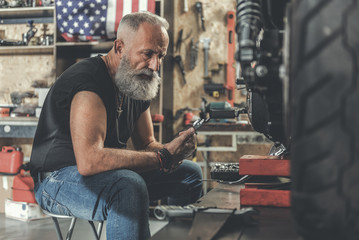 Serious old man in workshop - Powered by Adobe