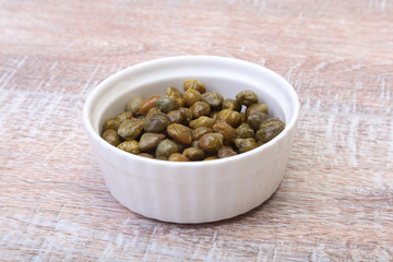 bowl with fresh capers on wooden table