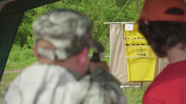 Blur back view of man shooting at yellow aim with animals drawn on it