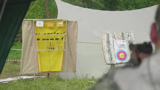 Blur back view of man shooting at yellow aim with animals drawn on it and is on target