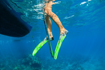 Kind in snorkelvinnen staat op duikers bootladder om onder water te duiken in tropisch koraalrif zeezwembad. Reislevensstijl, watersport buitenavontuur op familiezomer strandvakantie met kinderen.