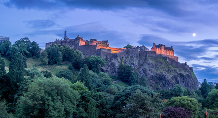 Fototapeta na wymiar View of Edinburgh Castle looming over the beautiful city of Edinburgh at night.