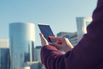 Detail of girl's hand while using touch screen on smartphone in Paris, France, La Defense.