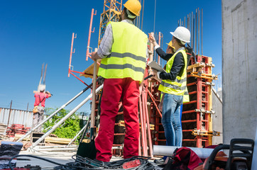Low-angle view of an experienced female architect or manager guiding the workers while supervising...