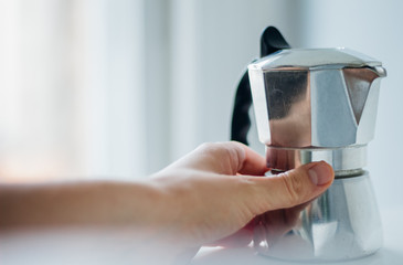 A hand reaching to an authentic Italian aluminium pot espresso maker