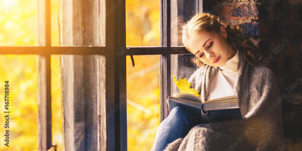 Poster Happy woman reading book by autumn window